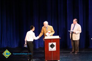 A student being congratulated as he receives his award at the 2014 Scholarship Awards Ceremony.