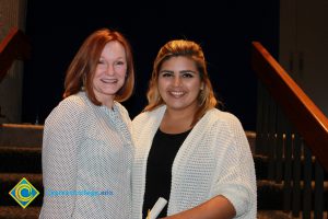 Woman with red hair and polka dot blouse with a young woman with a black shirt and white sweater.