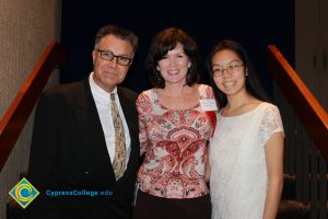 Lynn Mitts with a man in glasses and a dark jacket and tie and a young lady in a white dress.