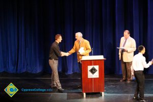 A student being congratulated as he receives his award at the 2014 Scholarship Awards Ceremony.