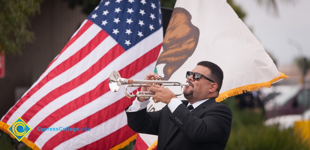 Gary Gopar playing trumpet next to American flag.