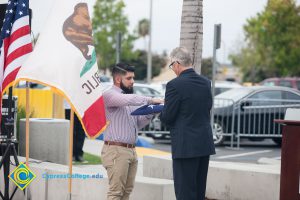 A bearded gentleman folds a flag held by Bob Simpson