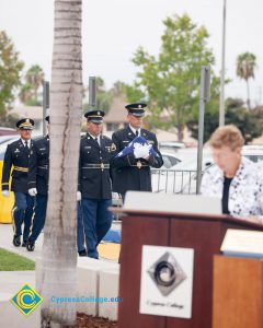 Military personnel carrying folded flag.