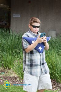 A young man holding a folded American flag.