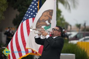 Gary Gopar playing trumpet with American flag flying next to him.