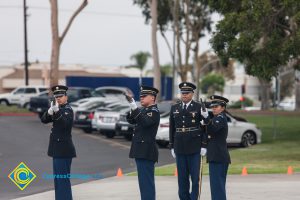 Military personnel in uniform, pointing rifles for salute.