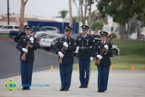 Military personnel in uniform, holding rifles.