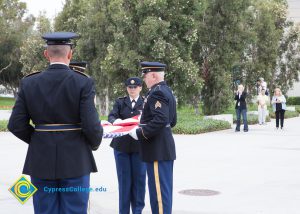 Military personnel folding American flag.