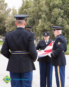 Military personnel folding American flag.