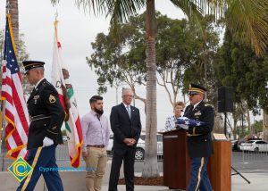 Military flag presentation with Bob Simpson and a bearded young man watching.