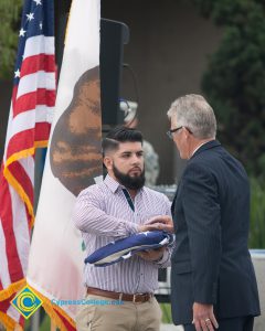 Bearded young man handing folded American flag to Bob Simpson.