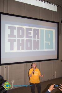 A woman in a yellow shirt speaking at the Ideathon event.