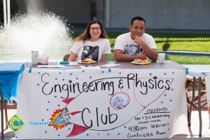 Students sitting at the Engineering & Physics Club table.