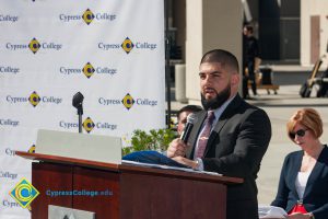 Man with a black beard and a suit speaking at the Veteran's Resource Center Groundbreaking.