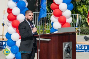 Man with a black beard and a suit speaking at the Veteran's Resource Center Groundbreaking.