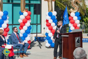 Man with a black beard and a suit looking back at Rick Rams as Dr. Schilling looks on at the Veteran's Resource Center Groundbreaking.