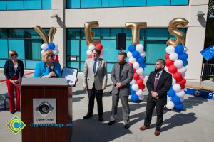 Three men n suits and Dr. Schilling look on as Dr. Cheryl Marshall speaks at VRC Groundbreaking.