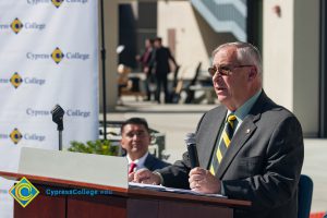 A man in a suit and tie speaking at the VRC Groundbreaking.