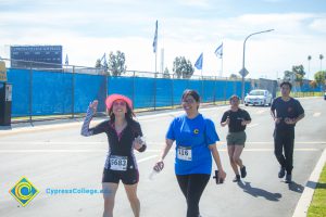 Three women and a young man running College Circle Drive.