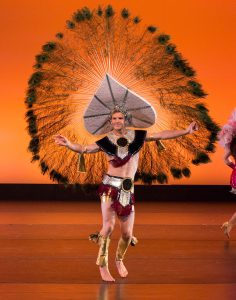 Dancer in a very large feathered headdress performing at the People in Motion concert.