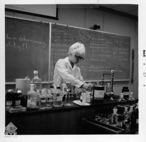 Black and white photograph of a student conducting a science experiment in class.