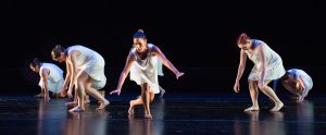 Dancers on stage wearing white dresses