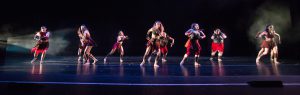 Dancers on stage wearing red and black costumes