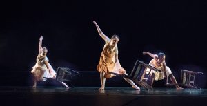 Dancers on stage wearing peach costumes and dancing with chairs