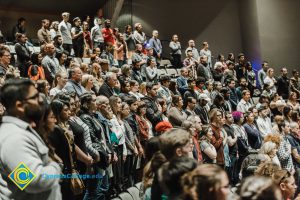 Audience at the Yom HaShoah event standing for the Pledge of Allegiance.