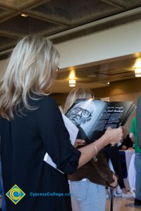 A woman dressed in black looks through the 2018 Yom HaShoah program.