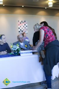 A woman holding a young child at a table with two older gentlemen.