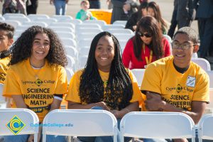 Four students wearing yellow Science, Engineering and Math shirts.