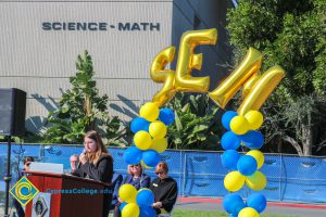 Young lady with long brown hair and glasses speaking to audience at SEM Groundbreaking ceremony.