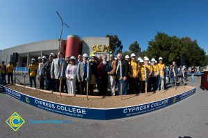 Group of people standing near shovels and dirt display box during SEM Groundbreaking ceremony.