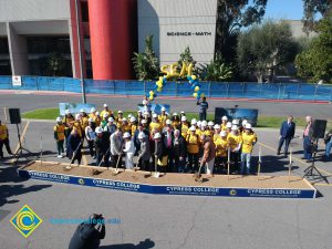 Group of people standing near shovels and dirt display box during SEM Groundbreaking ceremony.