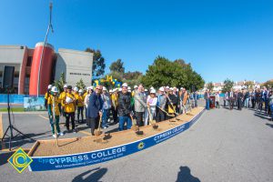 Group of people standing near shovels and dirt display box during SEM Groundbreaking ceremony.