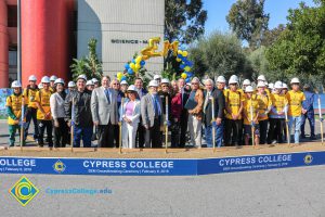 Group of people standing near shovels and dirt display box during SEM Groundbreaking ceremony.