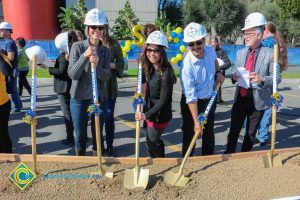 Group of people standing near shovels and dirt display box during SEM Groundbreaking ceremony.