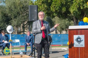 Man in suit and red tie speaking at SEM Groundbreaking ceremony.