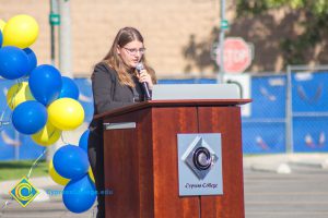 Young lady with long brown hair and glasses speaking to audience at SEM Groundbreaking ceremony.