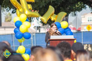 Young lady with long brown hair and glasses speaking to audience at SEM Groundbreaking ceremony.