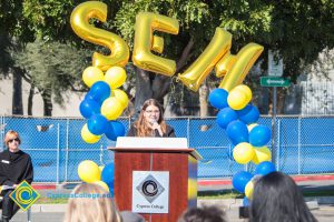 Young lady with long brown hair and glasses speaking to audience at SEM Groundbreaking ceremony.