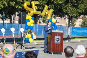 Man in a blue suit speaking to audience at the SEM Groundbreaking ceremony.