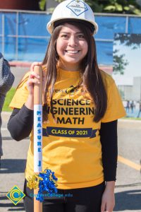 Young lady in a white hard hat, yellow t-shirt.