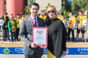 Dr. Schilling with a young man in a suit and tie holding a certificate.