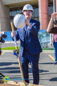 Richard Fee wearing a white hard hat, holding a white hard hat and shovel.