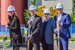 Group of three men in suits and a woman in black holding shovels at the SEM Groundbreaking event.