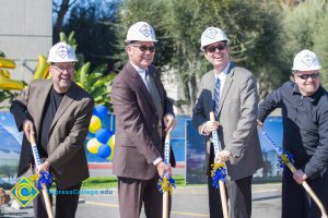 Men in suits and hard hats holding shovels.