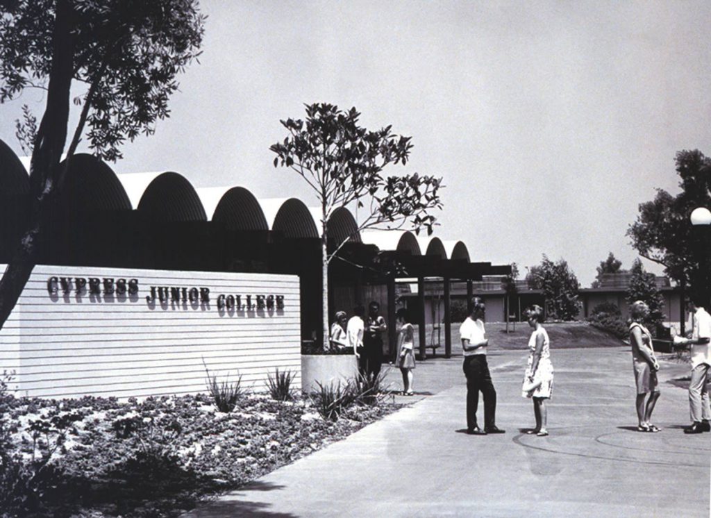 Vintage black and white photo showing students standing on campus next to the Cypress Junior College sign,
