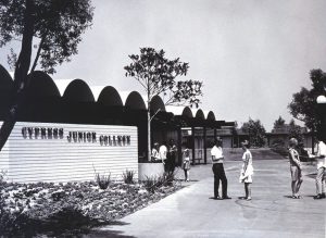 Vintage black and white photo showing students standing on campus next to the Cypress Junior College sign,